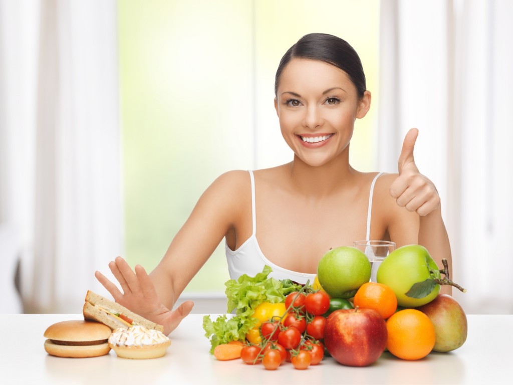 healthy and junk food concept - woman with fruits rejecting hamburger and cake